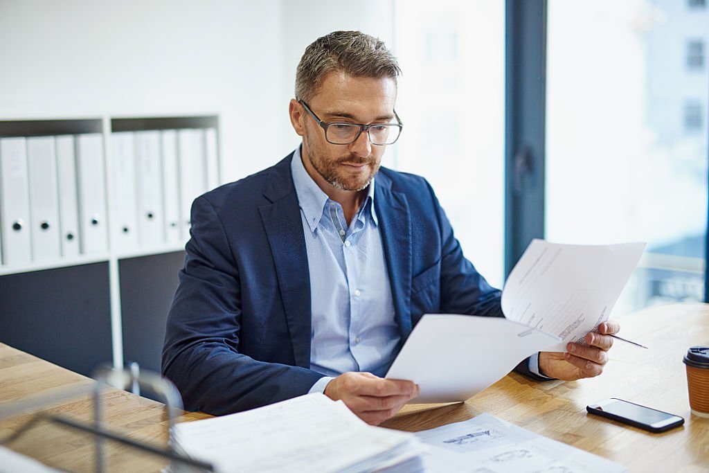 Shot of a mature businessman reading a document at his desk in an office